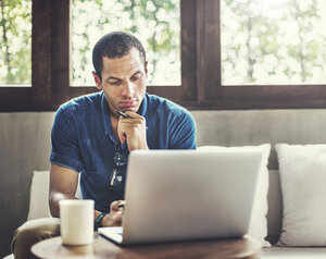 Man sitting in the couch and looking at his laptop